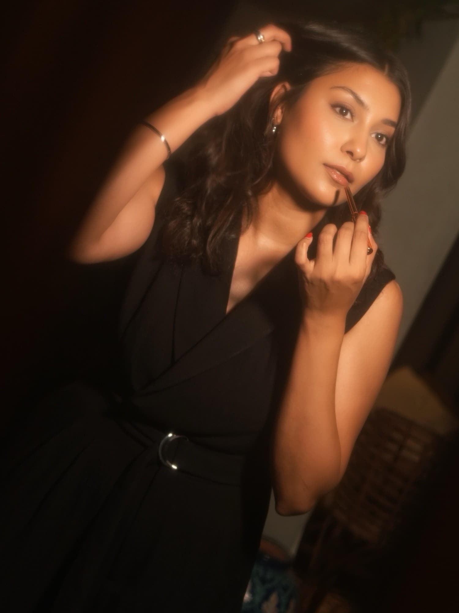 Shafaq applying lipstick in warm, low light