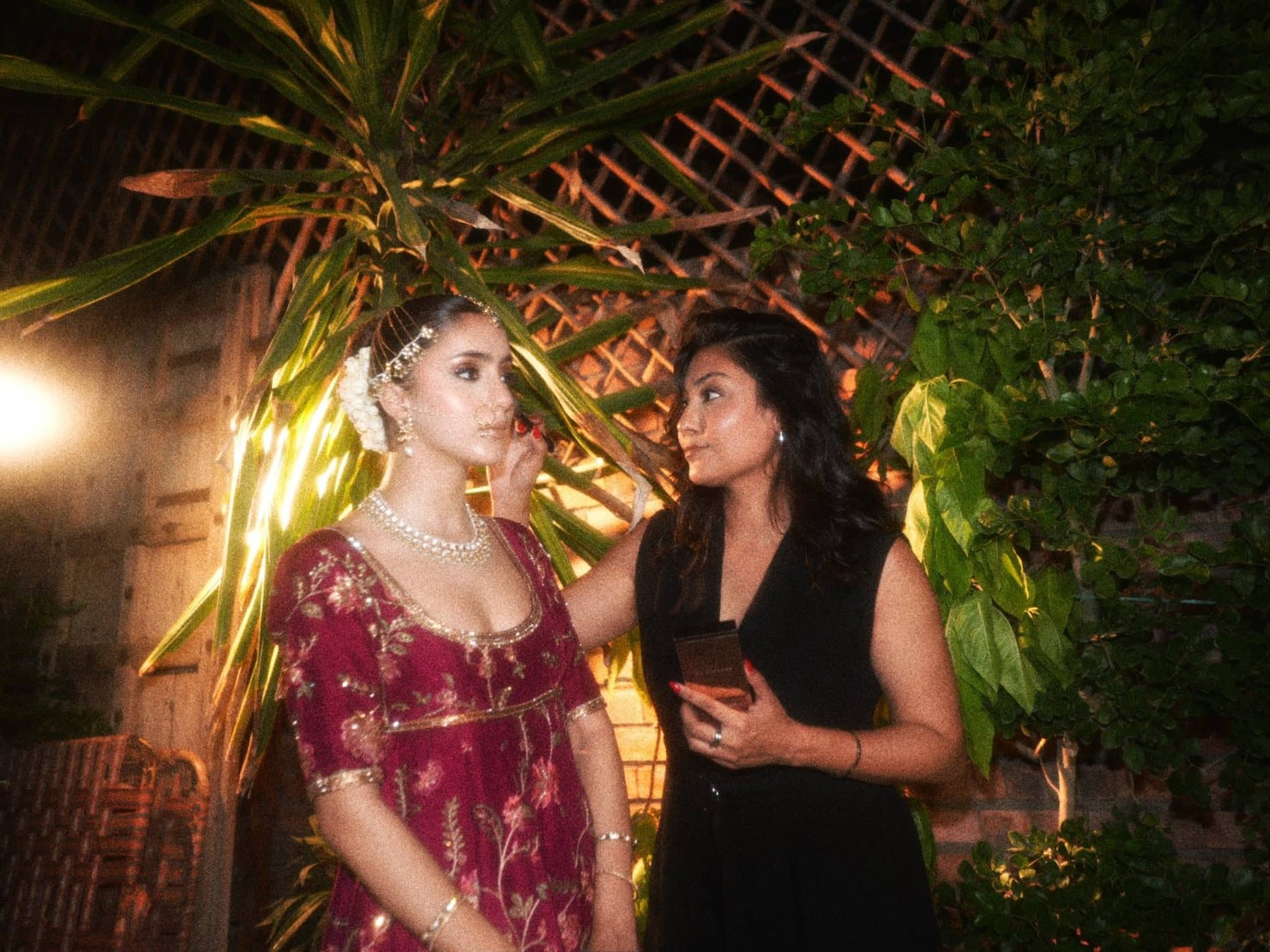 Shafaq touching up a bride's makeup at an evening event